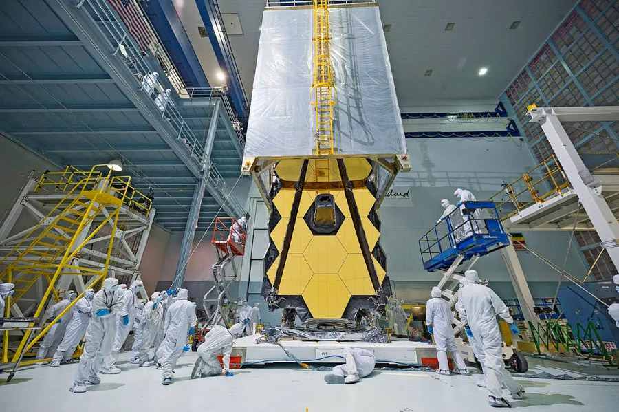 Wat eruitziet als een teleporter uit een sciencefictionfilm die over de James Webb-ruimtetelescoop van NASA is gedrapeerd, is in werkelijkheid een 'clean tent'. Deze clean tent beschermt Webb tegen stof en vuil wanneer technici van NASA's Goddard Space Flight Center de telescoop vanuit de relatief stofvrije cleanroom naar de testruimtes voor trillingen en akoestiek vervoeren.